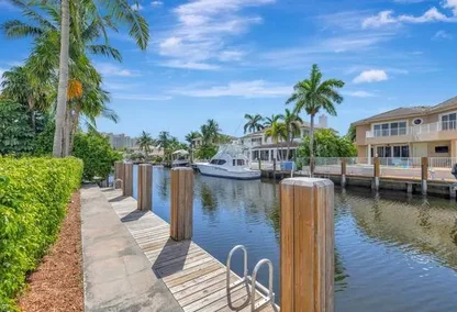 Private boat dock along a canal in Bel Marra, Boca Raton, with waterfront homes and palm trees under a blue sky.